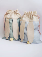 Učitaj sliku u preglednik galerije, bunny bags in sage green and baby blue linen with bunny ears and fluffy tail. Great to use as slippers bag, toys bag or diaper container.