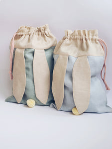 bunny bags in sage green and baby blue linen with bunny ears and fluffy tail. Great to use as slippers bag, toys bag or diaper container.