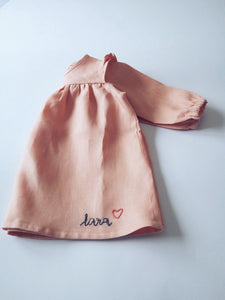 Korana linen long sleeves dress in peachy pink with customized hand embroidered name by Zekko Kids Clothes. Ruffles details on shoulders. Wooden buttons.