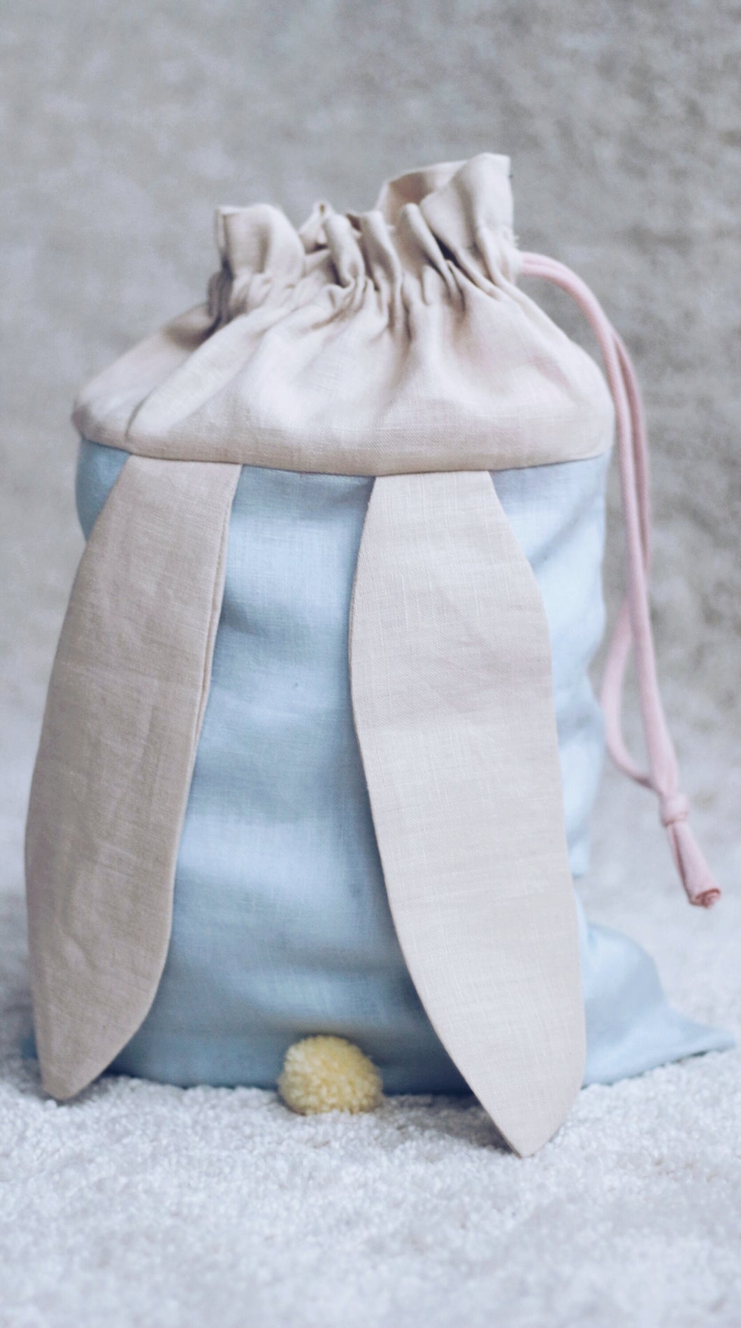 bunny bag in baby blue linen with bunny ears and fluffy tail. Great to use as slippers bag, toys bag or diaper container.